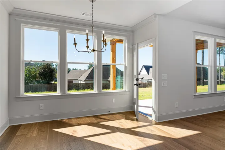 Warm sunlight streams across rich hardwood floors in this open dining area.