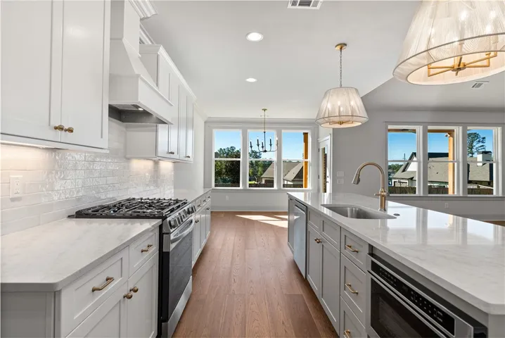 An open kitchen showcases clean cabinetry, durable stone countertops, and warm hardwood flooring.