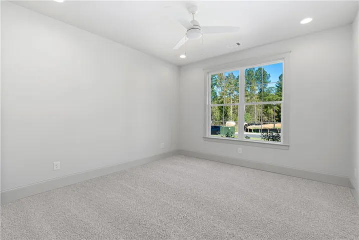Plush carpeting and a large window framing wooded views define this versatile space.