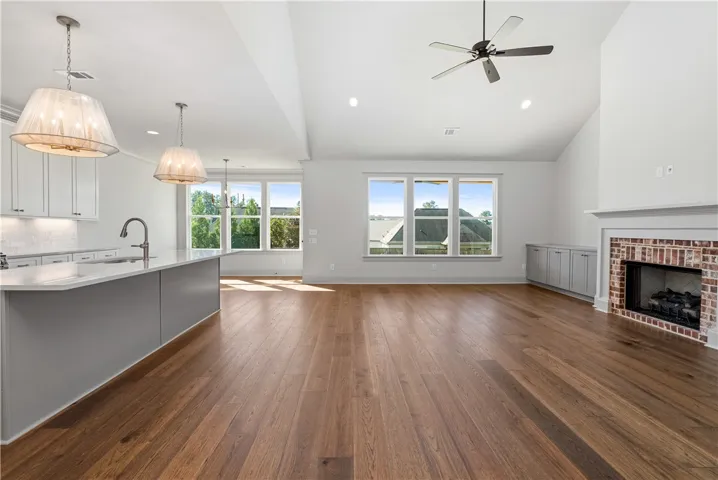 Rich hardwood flooring anchors this airy open floorplan, showcasing a classic brick fireplace.