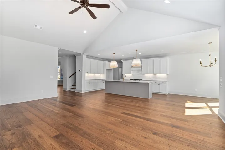 Rich hardwood floors anchor this open concept layout under high vaulted ceilings.
