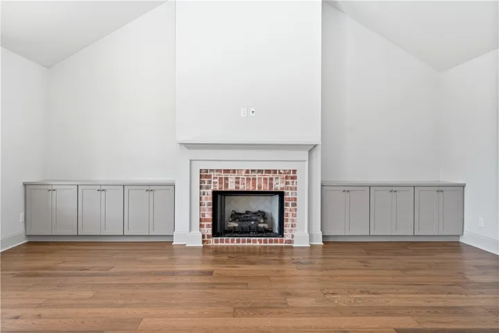 Rich hardwood floors complement a brick fireplace beneath vaulted ceilings.