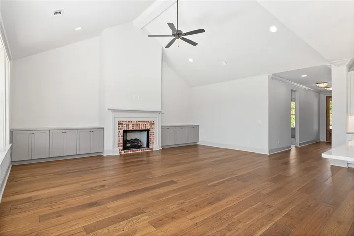 Gleaming hardwood floors and a brick fireplace anchor the airy living area with vaulted ceilings.