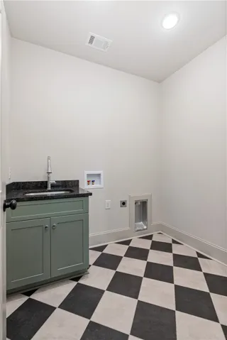 Checkerboard flooring and a functional utility sink define this dedicated home workspace.