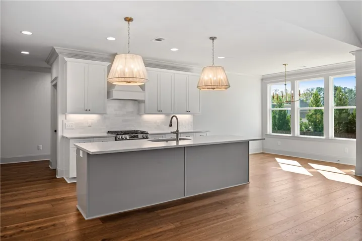 Rich hardwood flooring anchors the open culinary space featuring a large central island.