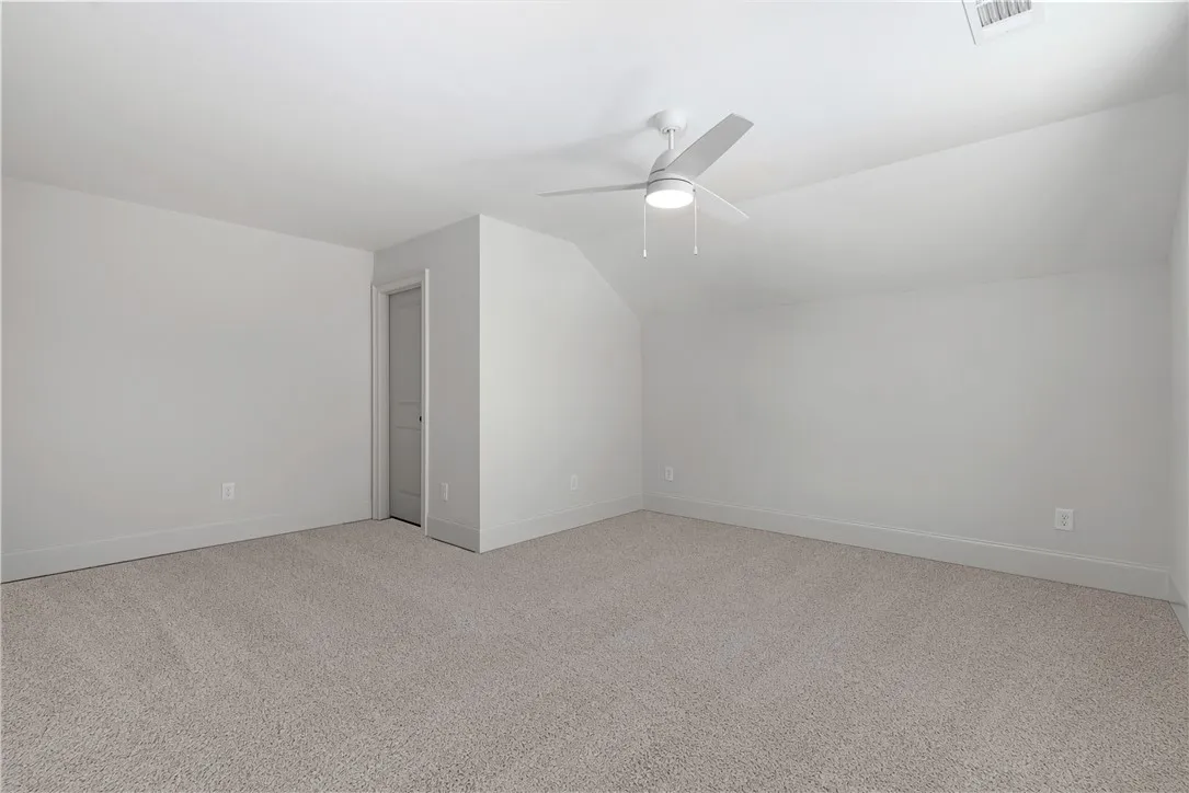 Soft carpeting pairs with crisp walls under a subtly angled ceiling in this upstairs bedroom.