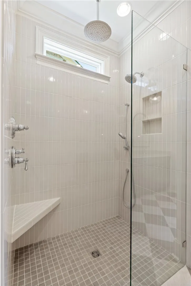 Floor-to-ceiling tile work and multiple showerheads create a refined spa-like walk-in shower.
