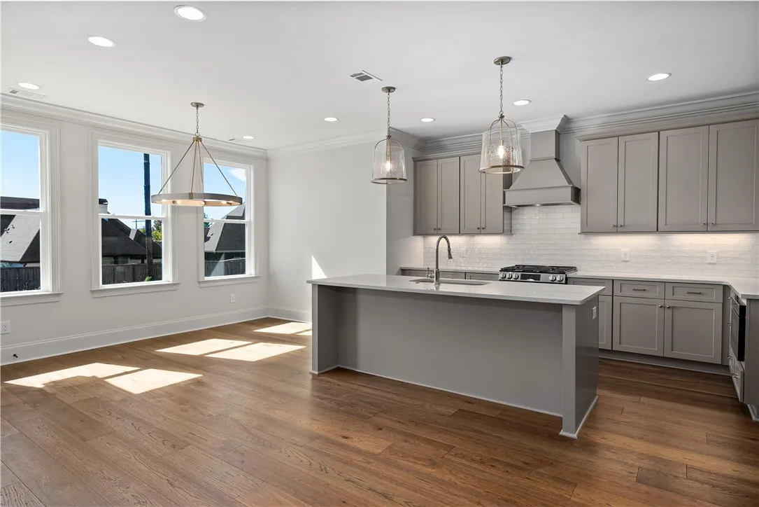Rich hardwood flooring complements custom cabinetry and professional appliances in this open-concept kitchen.