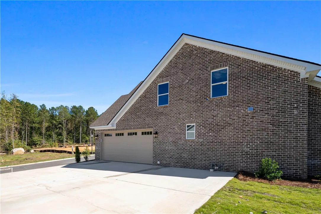 A spacious concrete driveway leads to an integrated side-entry garage flanked by classic brick masonry.