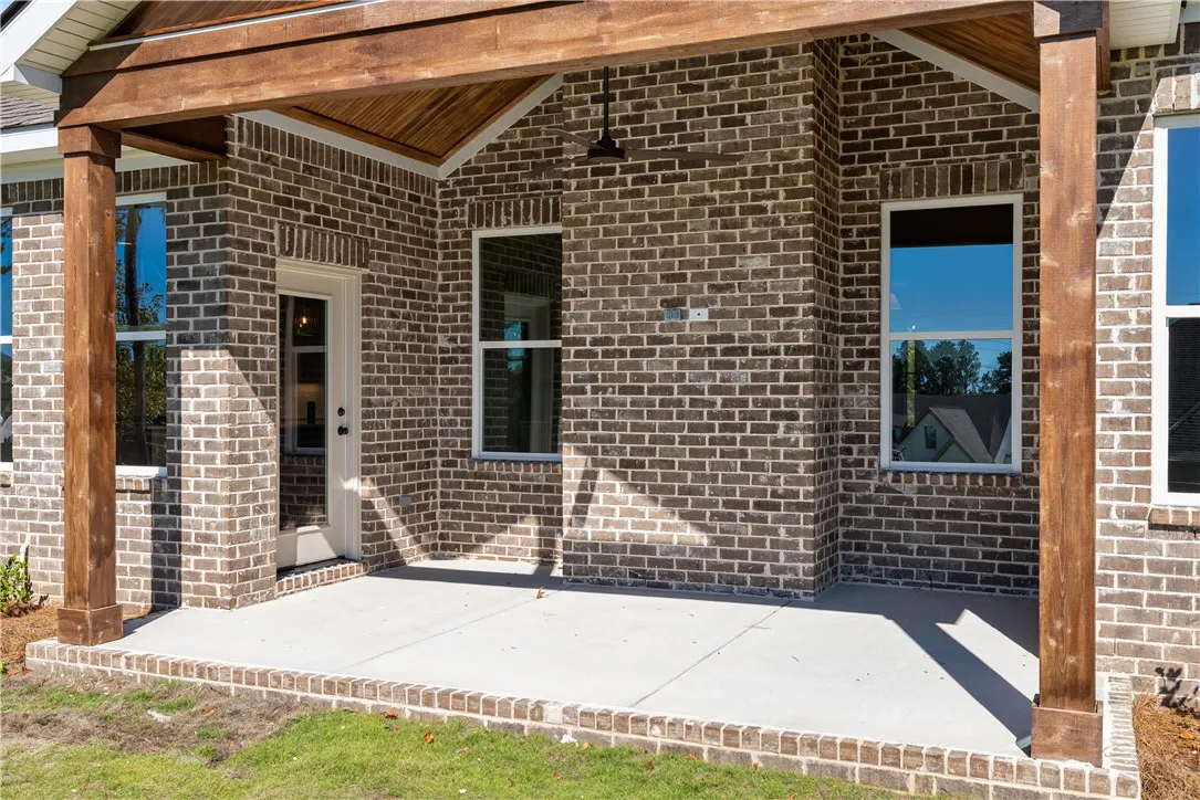 An inviting covered rear porch features timeless brick siding and warm wood ceiling accents.