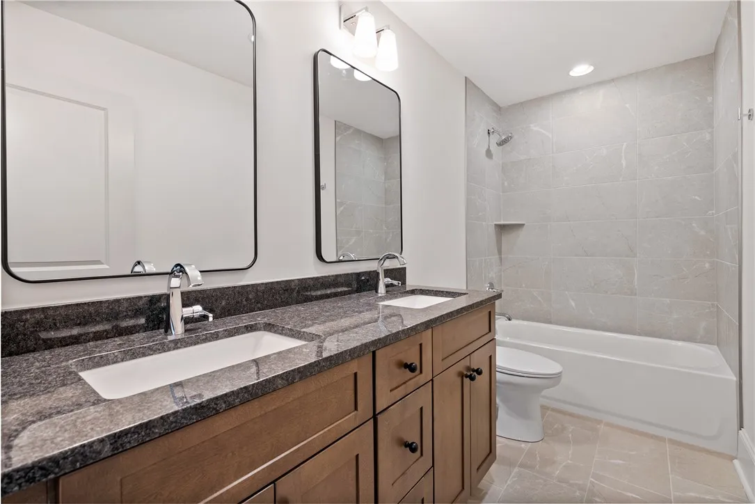 A modern double vanity anchors this beautifully tiled full bathroom.