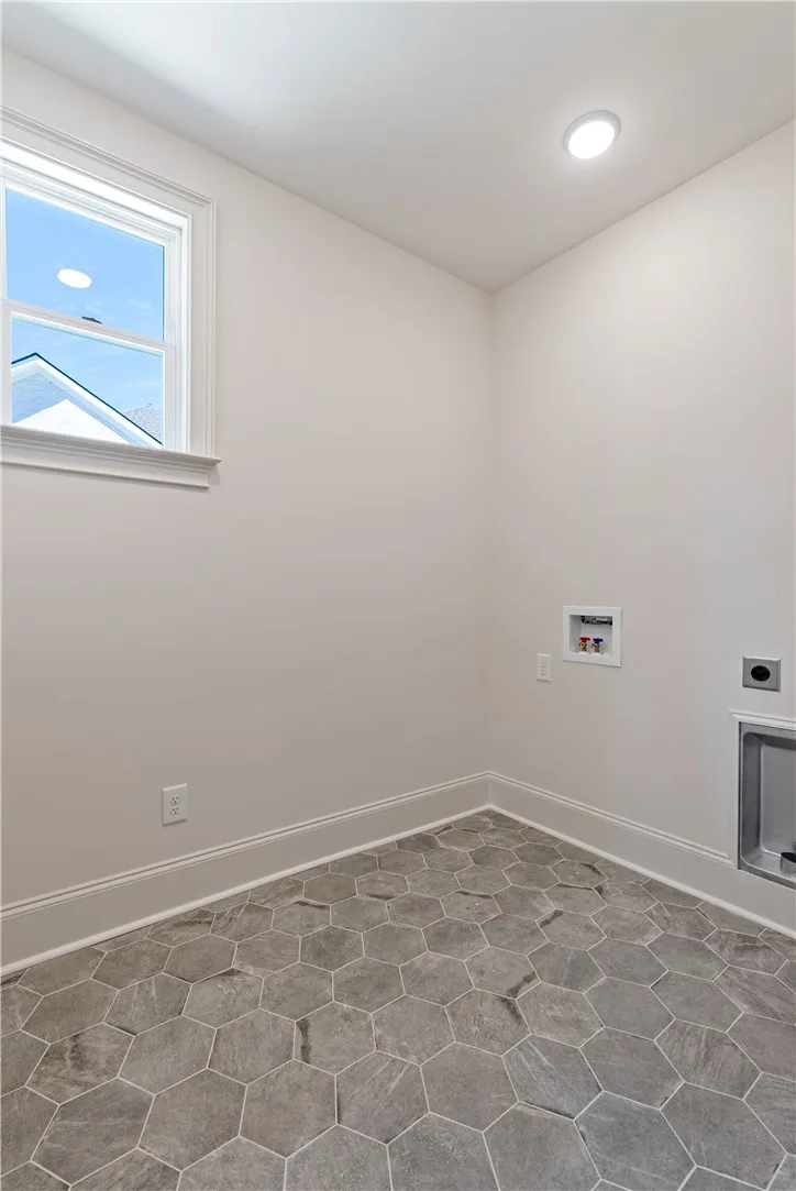 Hexagonal tile flooring and a bright window highlight this functional laundry space.