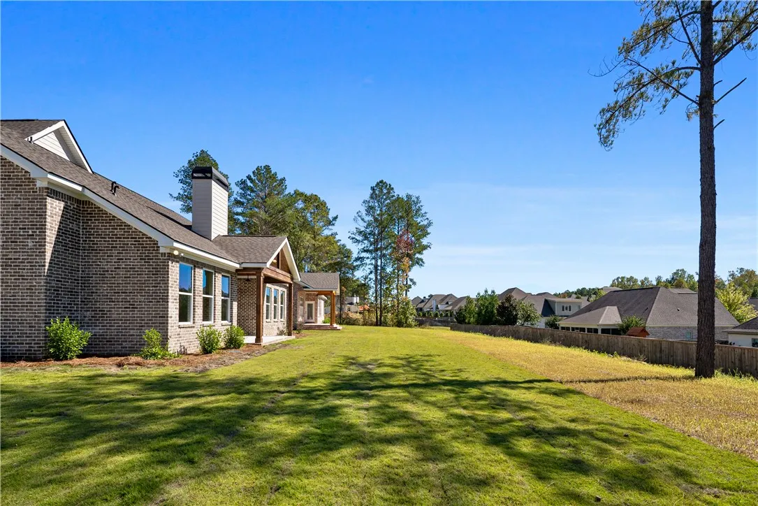 A spacious green lawn stretches alongside the classic brick exterior of the home.
