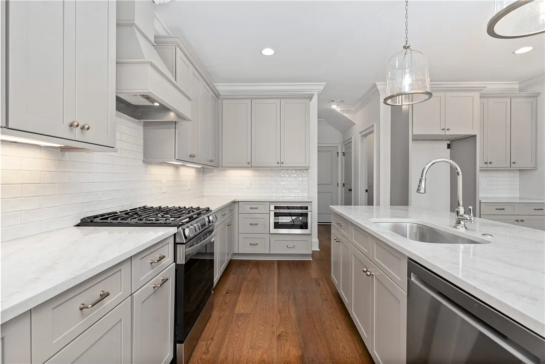 Rich hardwood floors contrast beautifully with clean shaker cabinetry and pristine stone countertops.