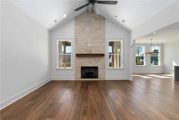 A floor-to-ceiling stone fireplace serves as the centerpiece of this vaulted great room with hardwood flooring.