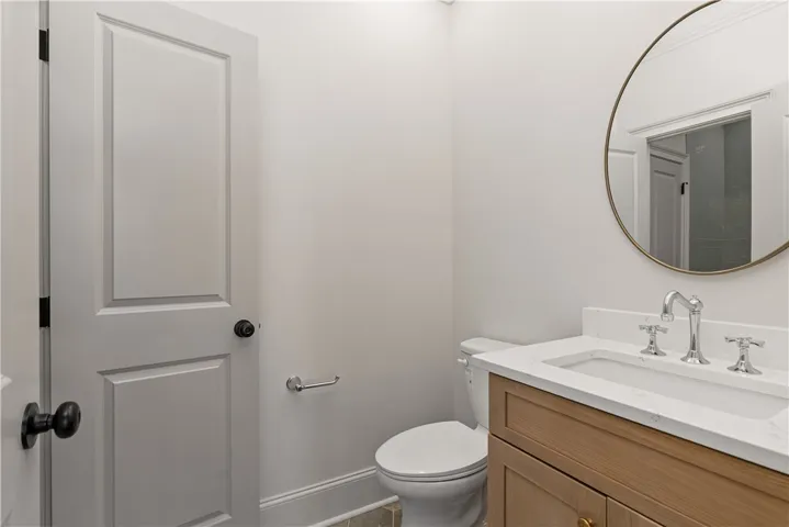 A refined powder room highlights a wood vanity topped with sleek stone counters.