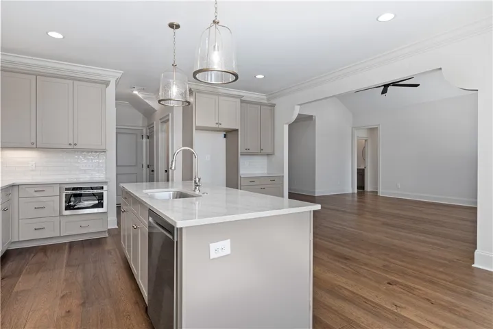 Rich hardwood flooring anchors this open kitchen layout containing built-in cabinetry and stone counters.