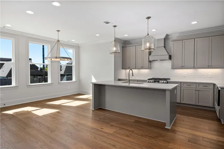 Rich hardwood flooring complements custom cabinetry and professional appliances in this open-concept kitchen.