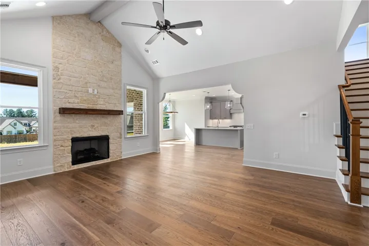 An impressive stone fireplace anchors the soaring living room with seamless flow to the kitchen.