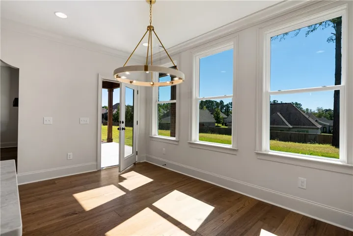 Warm hardwood floors complement the tall windows framing peaceful backyard views.