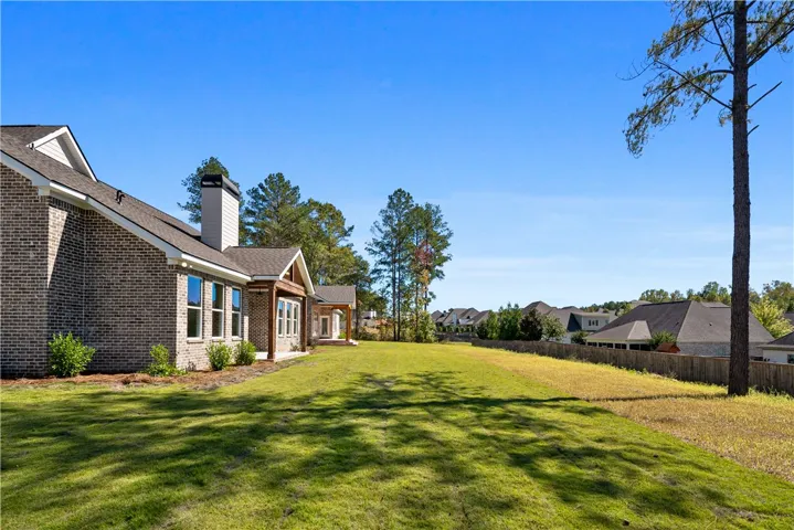 A spacious green lawn stretches alongside the classic brick exterior of the home.