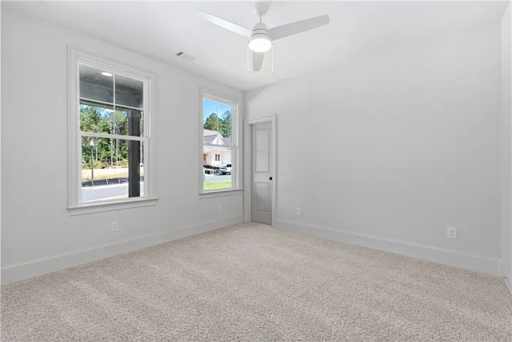 Large windows fill this carpeted bedroom with natural light.