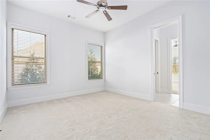 In bedroom 3, the bed is beautifully positioned between two tall windows, and the room enjoys direct access to a full bath.