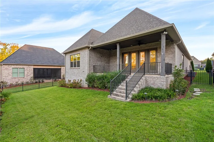 The yard, enclosed by a decorative aluminum fence, is thoughtfully landscaped.