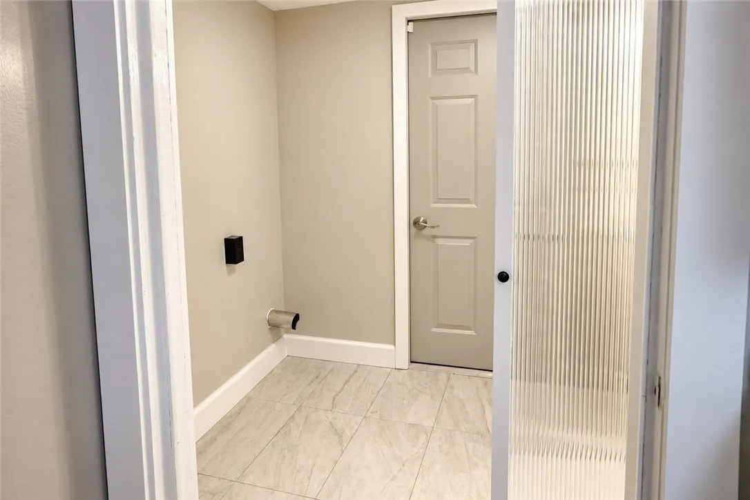 A dedicated utility space features clean tile flooring and a privacy glass pocket door.