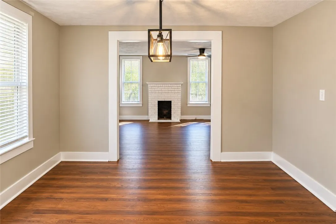 Warm wood flooring and classic wide trim frame the transition into a fireplace-warmed living space.