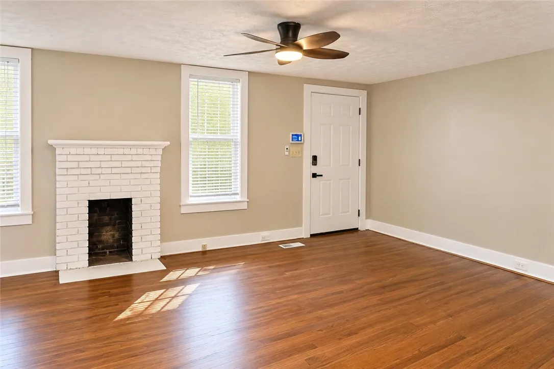 Rich wood flooring anchors this inviting living space anchored by a classic brick fireplace.