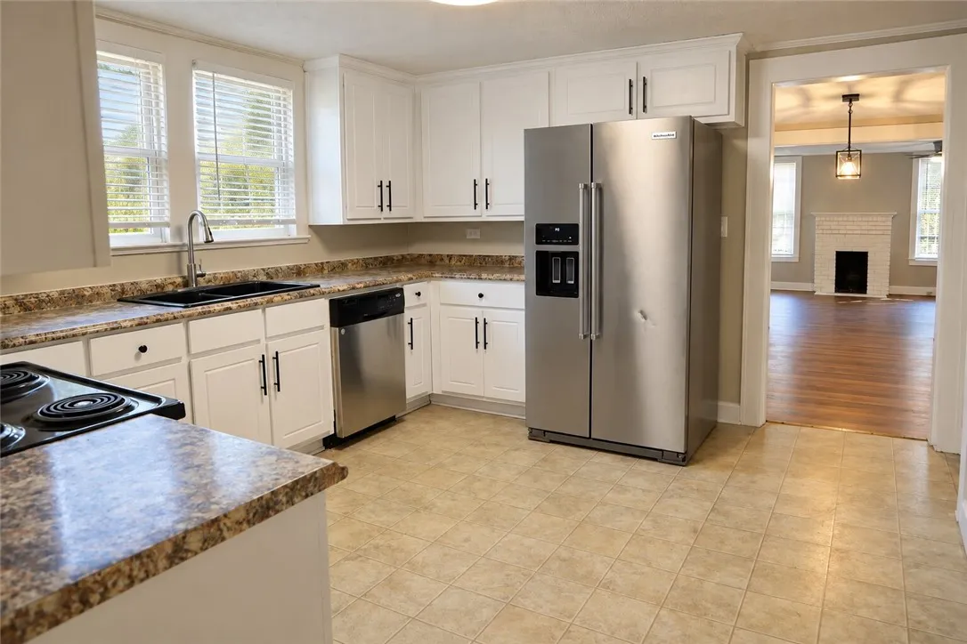 White cabinetry, stone-look countertops, and tile flooring define this functional kitchen workspace.