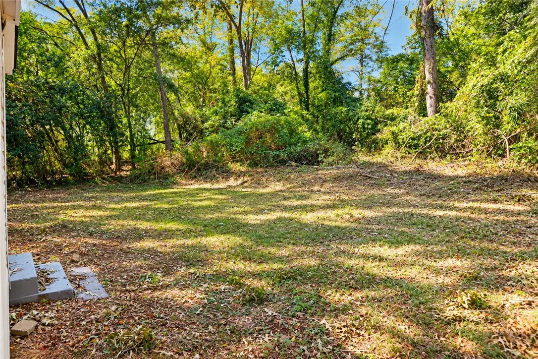 A spacious grassy yard sits framed by mature trees, offering a private outdoor retreat.