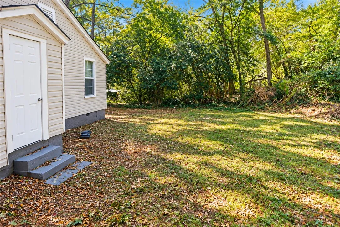 Mature trees frame a grassy lawn bordering the side of the home.