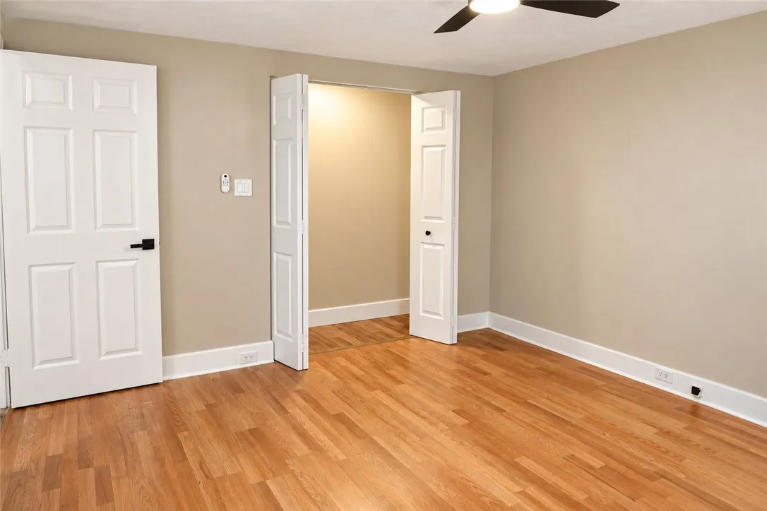 Rich hardwood flooring and classic multi-panel doors define this versatile, neutral-toned interior space.