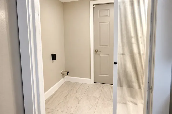 A dedicated utility space features clean tile flooring and a privacy glass pocket door.