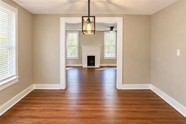 Warm wood flooring and classic wide trim frame the transition into a fireplace-warmed living space.