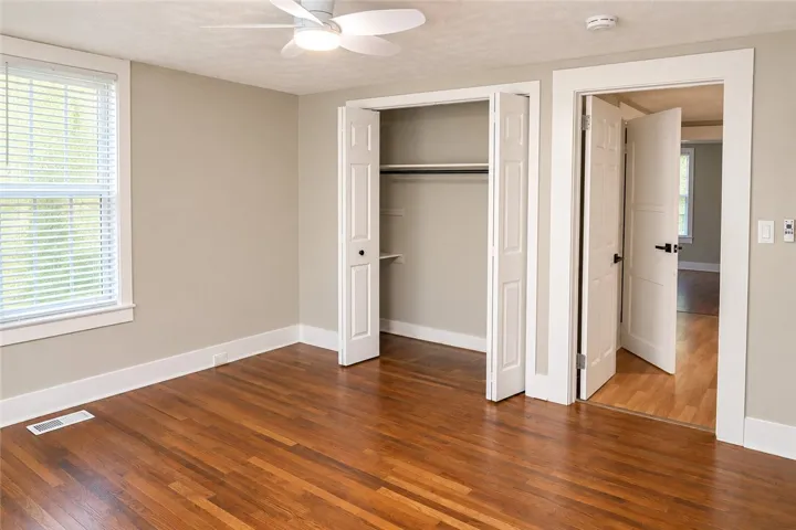 Rich hardwood flooring and classic white trim elevate this comfortable private bedroom.