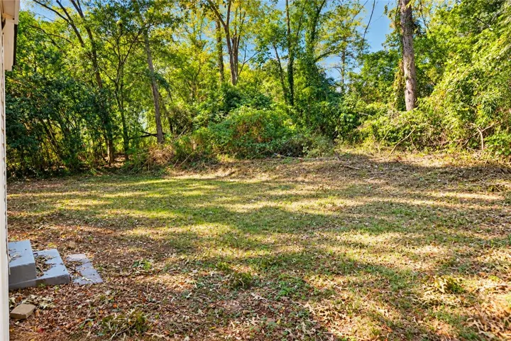 A spacious grassy yard sits framed by mature trees, offering a private outdoor retreat.