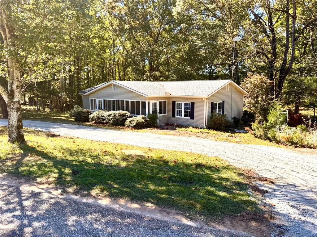 Wooded surroundings frame a classic ranch home with a spacious screened porch and mature trees.