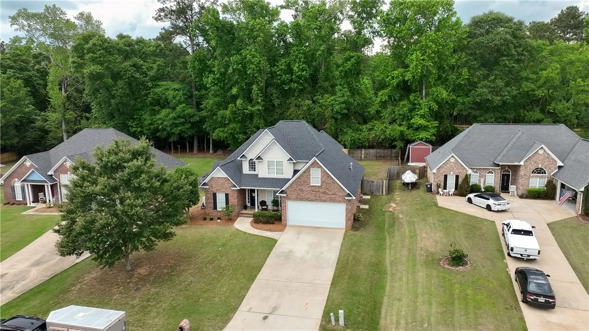 Stately brick exterior nestled among mature trees on a spacious suburban lot.