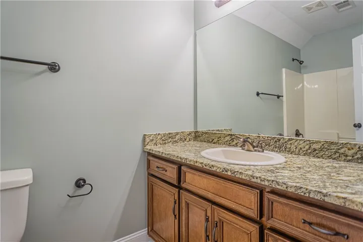 A spacious vanity features granite countertops paired with classic wood cabinetry.