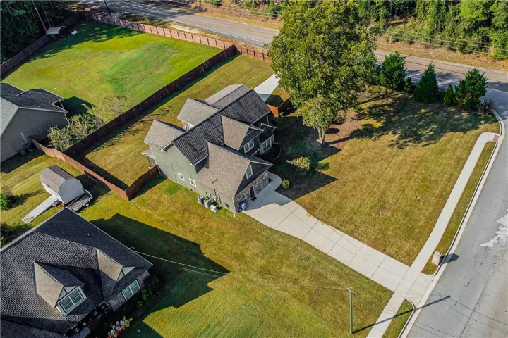 An aerial perspective showcases the spacious lot, fenced backyard, and private concrete driveway.