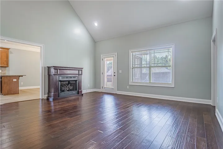 Rich hardwood flooring complements the vaulted ceiling and handsome fireplace in this inviting space.