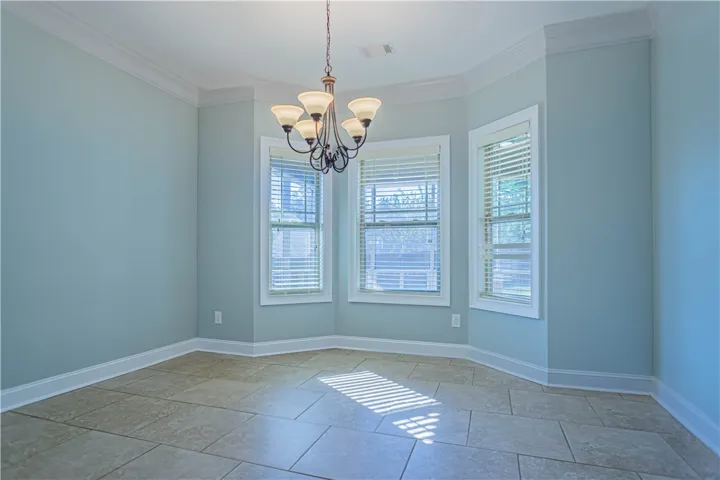 Elegant crown molding complements tile flooring and a bay window in this versatile space.