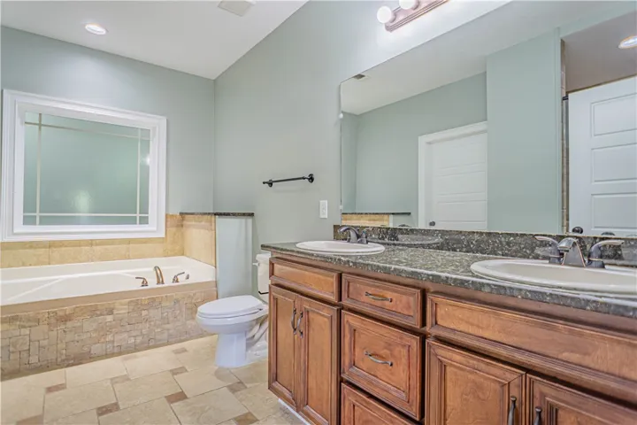 Tiled flooring, double vanity, and soaking tub anchor this spacious bathroom design.