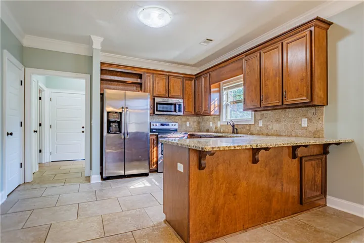 Rich wood cabinetry and stone countertops anchor this classic kitchen with tile floors.
