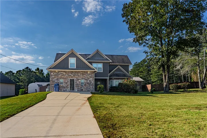 An inviting stone facade pairs beautifully with a concrete driveway on a grassy lawn.