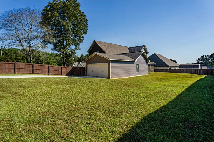 A fully fenced backyard offers a sprawling level lawn surrounding the detached multi-car garage.