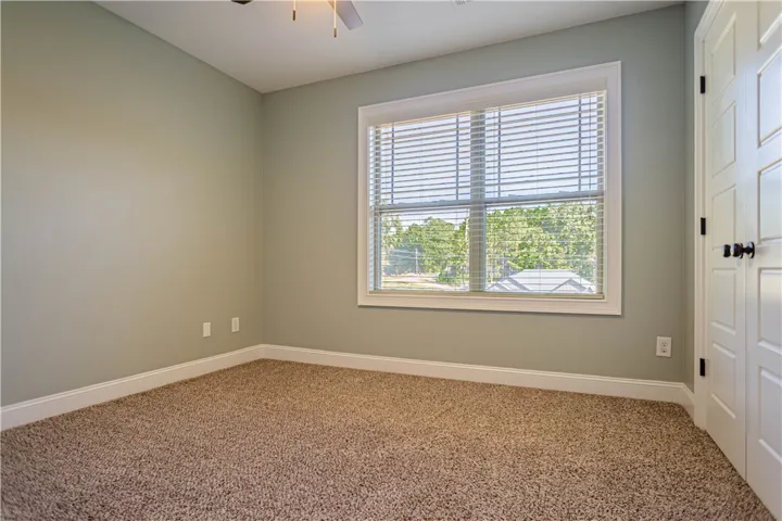 Soft carpet and a large window overlooking the outdoors define this versatile secondary bedroom.